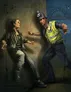 Police officer in yellow vest and helmet gestures toward seated woman in dark clothing.
