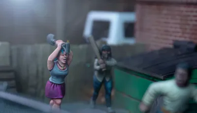 A dynamic scene features three miniature figures in a tense urban setting. In the foreground, a woman with blue hair raises a shovel, while a second figure behind her holds a baseball bat, both appearing ready to confront a threat. A third figure, dressed in a light shirt and blue pants, is seen running away, adding to the sense of urgency in the scene, with a green dumpster and a wooden fence in the background.