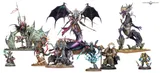 A collection of detailed miniatures from Games Workshop showcases a variety of characters. Prominently featured is a large, purple dragon-like creature adorned with armor and a regal headpiece, standing on a rocky base. Surrounding it are several other miniatures, including a skeletal figure with a glowing blue aura, a heavily armored Space Marine, and a smaller character in a mechanical suit, all displaying intricate designs and vibrant colors.