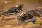 Two fierce war drakes of Rhûn are depicted, showcasing their armored backs adorned with golden spikes and intricate details. The drakes are positioned on rocky terrain with tufts of grass, one drake displaying a menacing expression while the other appears poised and alert. Their scales are a mix of dark green and brown, emphasizing their formidable presence in the Middle-earth setting.
