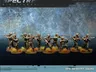 A group of ten miniatures representing a North Korean infantry squad is displayed, featuring soldiers in camouflage uniforms and helmets. They are equipped with Type 88 rifles and RPK-74s, with some holding rifle grenades. The base is adorned with tufts of grass, enhancing the military theme against a textured blue background.