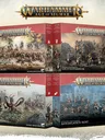 Four open box sets for Warhammer Age of Sigmar Battleforce collections. Top left: "Destruction Host" with armored warriors and a fortress under siege. Top right: "Grünta Stampede" featuring orcs and goblins charging. Bottom left: "Hammerhal" with a dragon and warriors in a snowy landscape.