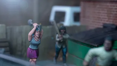 A dynamic scene features three miniature figures in a tense urban setting. In the foreground, a woman with blue hair raises a shovel, while a second figure behind her holds a baseball bat, both appearing ready to confront a threat. A third figure, dressed in a light shirt and blue pants, is seen running away, adding to the sense of urgency in the scene, with a green dumpster and a wooden fence in the background.