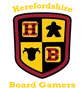 A shield-shaped logo features a divided design with four quadrants. The top left quadrant displays a red die with black dots, the top right features a black meeple, the bottom left shows a black cow silhouette, and the bottom right has a red die with white dots. The text "Herefordshire Board Gamers" is prominently displayed above and below the shield in a bold, yellow font.