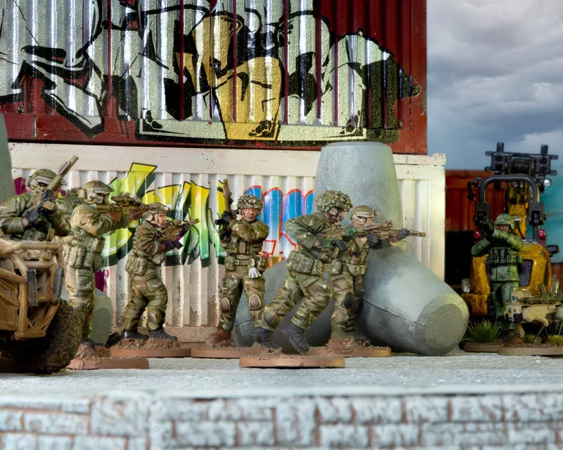 Five toy soldiers in camouflage aim rifles behind a graffiti wall.