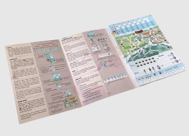 An open game booklet with a map of the Bordeaux wine region on the right page, featuring illustrated vineyards, towns, and a scoring track. The left page contains game rules, sections titled "Gather Resources," "Bases," "Vines," "Trellises," "Pass," and "Game End," along with diagrams of game components like coins, grapes, and barrels. The booklet is placed on a white surface.