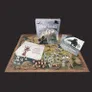 A boxed set titled "The One Ring: Starter Set" is prominently displayed, featuring artwork of a fantasy landscape with ruins and characters. Surrounding the box is a large, illustrated map depicting various locations, alongside several sheets of paper, including one with text and an image of a character. Scattered across the map are numerous illustrated cardboard figures and eight custom dice, enhancing the tabletop gaming experience.