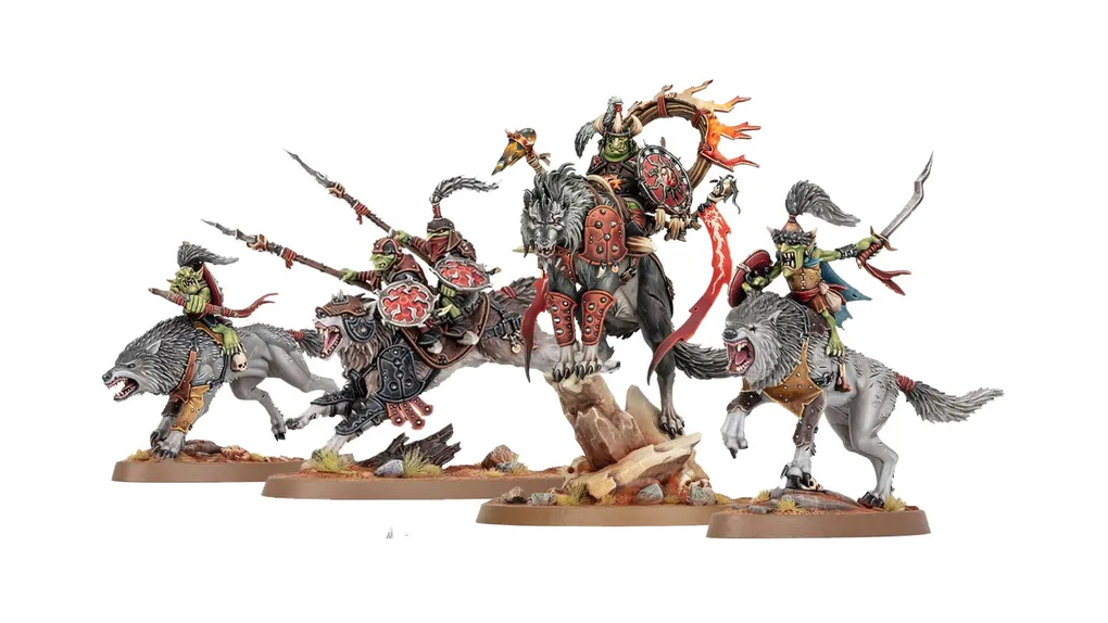A dynamic display of goblin miniatures features several wolf-riding figures, including a prominent leader adorned with armor and a fiery banner. The miniatures are intricately detailed, showcasing vibrant colors and various weapons, set against a rocky base with tufts of grass. Additional wolf-riders and a chariot can be seen, emphasizing the theme of mobility and aggression in this new release.