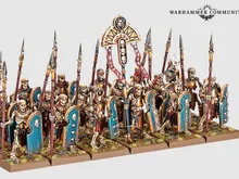 Miniature models of six skeleton chariots with detailed Nehekharan designs, each pulled by two skeletal horses. Chariots carry two skeletal warriors with spears and shields. Background shows skeletal warriors and archers in varied poses, some holding spears, others bows.