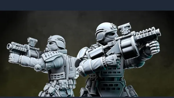 Two detailed miniatures from Anvil Industry's Special Forces range are positioned back-to-back, each holding futuristic firearms. The figures are clad in tactical armor with various pouches and equipment, showcasing a blend of sleek design and functionality. The miniatures are presented in a gray, unpainted finish, highlighting their intricate details and dynamic poses.