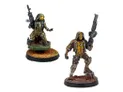 Two miniatures from Corvus Belli's upcoming releases are displayed. On the left, a figure in tactical gear holds a rifle, standing on a textured base, while on the right, another character in a similar outfit poses with a sidearm, set on a rocky base. Both miniatures feature intricate details and a color palette of earthy tones and metallic accents, showcasing their sci-fi aesthetic.