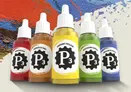 Four bottles of P3 Paints are prominently displayed against a colorful, textured background. The bottles include Menite Ochre, Radiant Yellow, Witchfire Green, and Frostbite Violet, each featuring a distinctive label with the P3 logo. The vibrant colors of the paints contrast with the dynamic splashes of paint in the background, highlighting the artistic theme of the image.