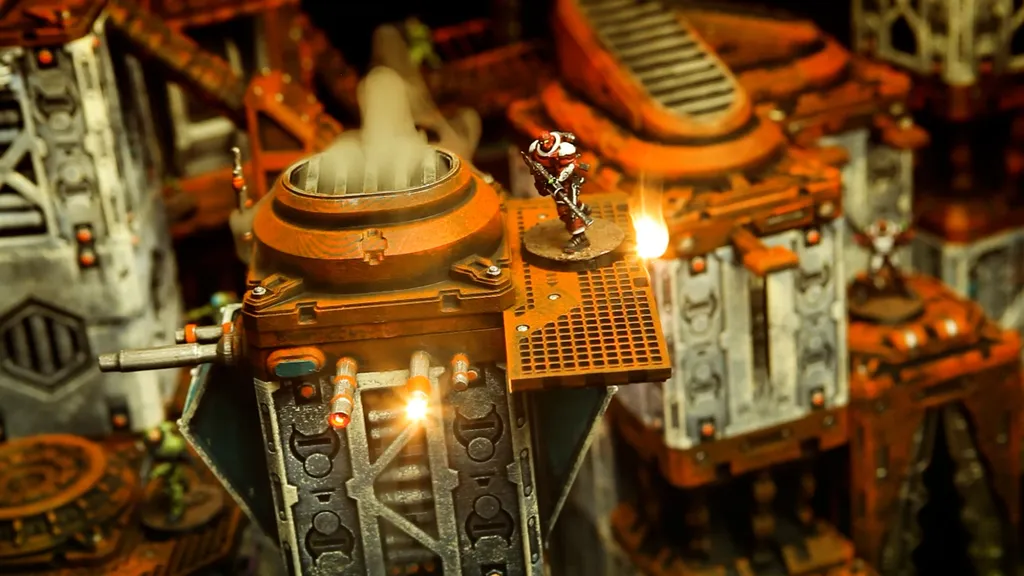 Miniature sci-fi figure in orange and white armor standing on a small platform atop an industrial terrain piece. Background shows metal pipes, grates, and a smokestack emitting vapor. Warm lighting highlights the scene.