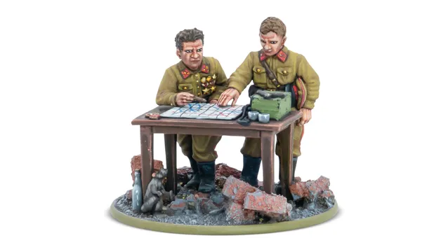 A detailed miniature scene features two Soviet officers, one with a map and the other pointing at it, engaged in strategic planning. They are dressed in military uniforms with insignia, standing beside a table cluttered with a map, a green box, and other items. The base is set on a rubble-strewn ground, with a small animal visible in the foreground, enhancing the war-torn atmosphere.