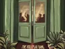 A green double door with glass panels, slightly ajar, showing silhouettes of people inside a dimly lit room. Above the door, a backlit sign reads "AMICI DI SEMPRE" in large, elegant letters, with a smaller sign below it reading "RULEBOOK" in bold, red letters. The door is framed by green curtains, and decorative plants with large leaves flank the base of the door.