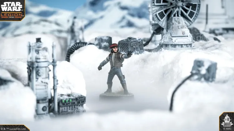 A Rebel Officer stands prominently in a snowy landscape, wearing a brown jacket and a red cap, with one hand raised as if giving orders. In the background, a detailed speeder truck and various mechanical structures are partially obscured by snow, creating a wintry atmosphere. The scene is set against a backdrop of distant mountains under a clear blue sky.