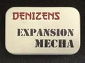 A small, silver tin features the text "DENIZENS" in bold red letters at the top and "EXPANSION MECHA" in large, black, stencil-style font below. The tin's surface has a smooth, metallic finish, and it is set against a dark background, emphasizing its compact and portable design. This packaging represents the new expansion for the Space Denizens wargame, which includes mechs and terrain features.
