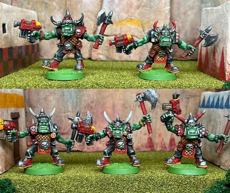 A group of five 28mm scale space orc miniatures stands on a grassy terrain, showcasing their vibrant colors and detailed designs. Each orc is heavily armed, wielding a mix of axes and futuristic guns, and adorned with skull motifs and horned helmets. The background features a stylized, rocky landscape with colorful banners, enhancing the dynamic and adventurous theme of the scene.