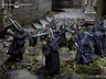 A dynamic scene depicts a confrontation between a group of cloaked figures, resembling Ringwraiths, and a diverse band of heroes from The Lord of the Rings. The heroes, including characters like Aragorn and Frodo, are positioned in a ruined stone setting, surrounded by overgrown foliage and debris. The Ringwraiths, dressed in dark, tattered cloaks, wield swords, creating a tense atmosphere as they face off against the protagonists. The intricate details of the miniatures highlight their distinct features and expressions, enhancing the narrative of this iconic moment.