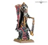 Miniature of a skeletal warrior figure with ornate armor, holding a chain with a skull end, a red cloak, and a staff. Detailed headdress with gemstones and a black mask. Standing on a rocky base with green moss.