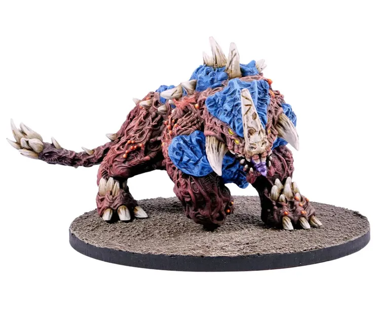 A detailed miniature of a Plague Colossus, a large, monstrous creature, is depicted on a textured base. The creature features a rugged, reddish-brown body with blue armor-like plates and prominent spikes, showcasing a fierce expression with sharp teeth and glowing eyes. Its muscular limbs and claws emphasize its intimidating presence, making it a striking addition to any sci-fi wargaming setup.