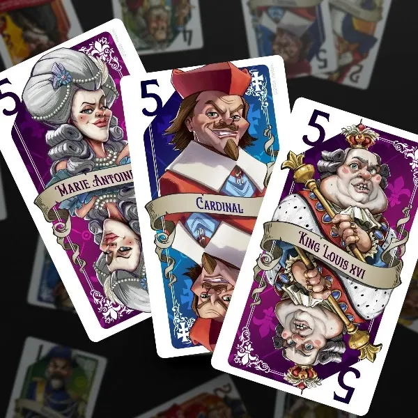 Three tarot-sized noble cards from the game Guillotine are displayed prominently. The cards feature stylized illustrations of historical figures: Marie Antoinette with elaborate hair and a confident expression, a Cardinal with a distinctive red hat and a sly grin, and King Louis XVI, depicted with a round face and regal attire. Each card is adorned with a purple background and the number "5" in the corner, indicating their point value. In the background, additional cards are faintly visible, hinting at the game's colorful and thematic design.