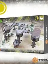 A box for the "Industrial Stilt Pods" set from TTCombat features a detailed illustration of modular pods, stilts, and walkways arranged in an elevated complex. The design includes one large pod and two smaller pods connected by five walkways and six platforms, all set against a textured ground. The packaging prominently displays the TTCombat logo and the "Industrial Hive" branding.