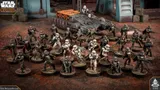 Miniature soldiers in armor and a gray tank on a muddy battlefield.