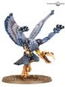 Miniature of a Greater Daemon of Tzeentch with blue-grey skin, golden wings, and ornate armor. Standing on a round base, holding a staff in one hand and a skull-like head in the other. Text in top right corner reads "Warhammer Community."