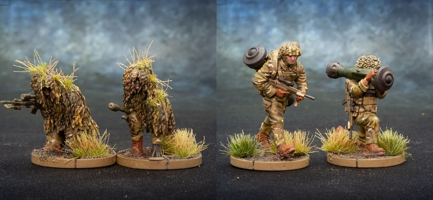 Two detailed miniature soldiers are depicted on circular bases with tufts of grass. The first soldier, on the left, is dressed in camouflage and carries a rifle, while a backpack is slung over his shoulder. The second soldier, on the right, is also in camouflage and is shouldering a weapon system, possibly a missile launcher, with foliage attached for camouflage. The background features a gradient of blue and gray, enhancing the focus on the miniatures.