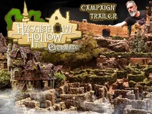 Miniature fantasy landscape with stone castle ruins, winding hedge maze, and rocky terrain. A bearded man in a black shirt leans over the display. Text reads: "CAMPAIGN TRAILER" and "Hagglethorn Hollow."