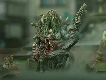 Green-skinned monster with long hair, horns, and a staff, holding a severed head.