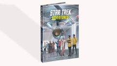 A roleplaying game sourcebook titled "Star Trek Adventures" features a colorful cover with a futuristic starship and various characters in a sci-fi setting. The characters, including humanoids of different species, are depicted in a range of outfits, suggesting a diverse crew. The title and subtitle are prominently displayed at the top and bottom, with the publisher's logo visible on the spine.