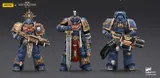Three detailed action figures from the Warhammer 40,000: Space Marine series are displayed against a dark background. On the left, the Relic Primus Armor figure holds a heavy bolt rifle, adorned with intricate decorations, including a skull emblem and a shield. To the right, the Heavy Artificer Armor figure wields a large combat blade, featuring a flowing red cape and various honor ribbons, showcasing the iconic blue and gold color scheme of the Ultramarines chapter.