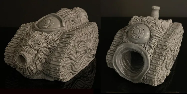 A grotesque tank model designed for a Chaos army, featuring a textured surface adorned with various orifices, boils, and an eye-like detail on the front. The tank has a large, gaping mouth-like opening, emphasizing its disturbing aesthetic. The model is presented in a gray, unpainted finish, showcasing intricate sculpting details that highlight its bizarre and unsettling design.