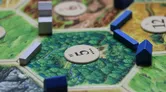 Board game piece on green textured mat with "LO" and dots.