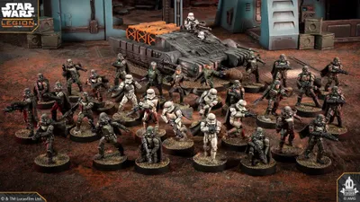 Miniature soldiers in armor and a gray tank on a muddy battlefield.