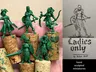 A hand holding several green, unpainted miniatures stands atop cork bases, showcasing a variety of female fantasy characters, including warriors and rogues. Each figure is intricately detailed, with distinct poses and weapons, such as swords and bows. To the right, a sketch of a female warrior is displayed, accompanied by the text "Ladies Only" and "hand sculpted miniatures" at the bottom.
