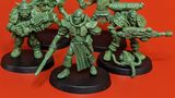 A group of five 28mm scale sci-fi miniatures is displayed against a bright red background. The figures include a Space Commando wielding a rifle, a Starchild with a distinctive helmet, an Assault Goar holding a sword, a Space Orc with a large gun, and a Voidborn equipped with various gadgets. Each miniature features intricate details and a classic old-school aesthetic, showcasing the unique character and charm of the RT Adventurer Pack II from Satyr Art Studios.