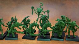 A collection of old school miniatures from Satyr Art Studio, featuring various fantastical creatures in a vibrant green color. The figures include beastmen with distinct features such as horns and claws, some wielding weapons, and a central figure holding a staff topped with a skull and a crescent. They are displayed on black bases against a warm, textured background.