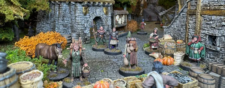 A bustling village scene features a variety of 28mm scale, white metal miniatures representing ordinary townsfolk engaged in daily activities. Characters include a barmaid, a farmer, and a woman carrying a basket, surrounded by barrels, pumpkins, and a horse, all set against a backdrop of stone buildings and lush greenery. The detailed miniatures bring to life the vibrant atmosphere of a fantasy RPG setting, showcasing the charm of incidental NPCs.