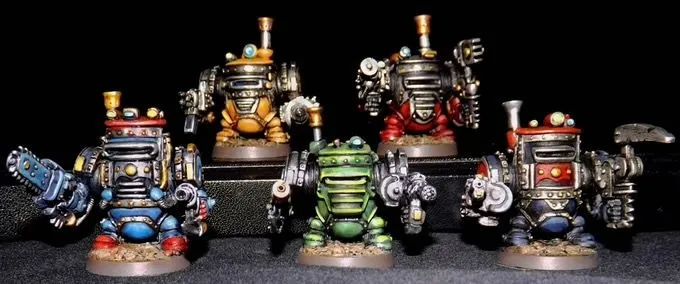 A group of five colorful, multipart miniatures representing armoured dwarves, each with distinct sci-fi and steam-driven designs. The miniatures feature various colors, including blue, green, red, and yellow, with intricate details like gears and pipes, and are equipped with different weapons. They stand on circular bases against a dark background, showcasing their unique character and craftsmanship.