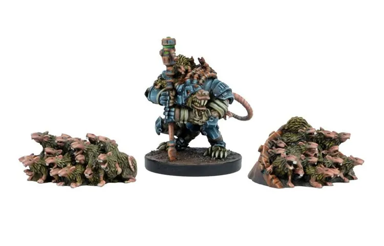A detailed miniature of a Verr-Myn character stands prominently in the center, clad in blue armor with a large, menacing head resembling a rat. The character holds a staff and has a tail extending behind it. Flanking the main figure are two piles of smaller, rat-like creatures, depicted in various shades of brown and green, suggesting a swarm ready to engage in battle. The base is textured to resemble a rugged terrain, enhancing the overall dynamic of the scene.