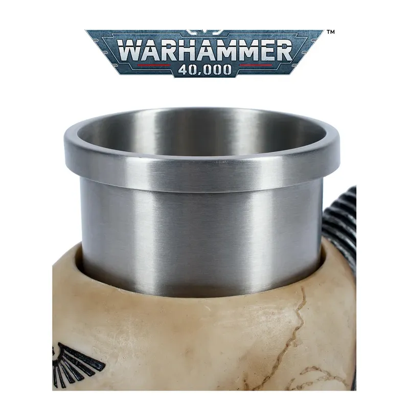 Silver metal mug with a smooth, reflective surface, featuring a rolled rim and a black coiled cord attached to its side. The mug sits atop a beige, textured object resembling a stylized skull, which has a small rectangular plate with three bolts on its side. In the background at the top, a metallic banner displays the text "WARHAMMER 40,000" in bold, futuristic lettering.