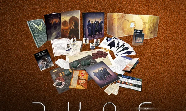 A collection of items from the Dune RPG Physical Megabundle is displayed against a textured brown background. The assortment includes various books, game components, and promotional materials, prominently featuring the Dune logo and the text "Supporting: ACLU." The items are arranged in a visually appealing manner, showcasing the core rulebook, adventure modules, and other game accessories.