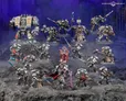 A detailed display of Black Templar miniatures showcases a variety of armored figures in silver and black, set against a dark, rocky backdrop. Prominent in the scene is a Venerable Dreadnought on the left, flanked by a mix of characters including the Emperor’s Champion, Bladeguard Veterans, and Sword Brethren, all wielding swords and other weapons. The figures are intricately painted, with some holding banners and others poised for battle, creating a dynamic and imposing presence.