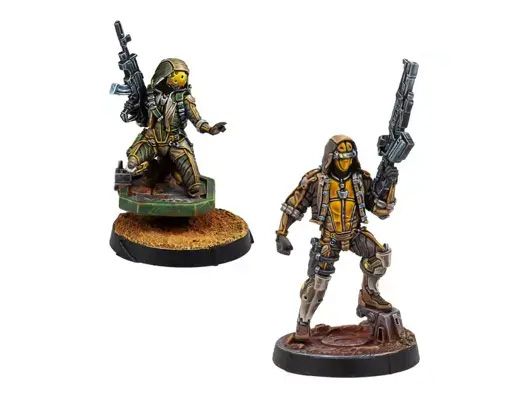 Two miniatures from Corvus Belli's upcoming releases are displayed. On the left, a figure in tactical gear holds a rifle, standing on a textured base, while on the right, another character in a similar outfit poses with a sidearm, set on a rocky base. Both miniatures feature intricate details and a color palette of earthy tones and metallic accents, showcasing their sci-fi aesthetic.