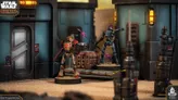 A customisable Separatist Super Tactical Droid stands prominently on a sandy surface, showcasing its multipart design with a metallic body, red accents, and a distinctive head. It is positioned near a futuristic structure with a large door and control panel, while a second droid, holding a weapon, is partially visible in the background. The scene is set in a sci-fi environment, typical of the Star Wars universe, with detailed textures and colors enhancing the overall aesthetic.
