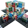 A wooden cube puzzle game with 27 interlocking cubes in six colors: blue, green, red, beige, black, and white. Cubes display patterns labeled Forest, Ocean, Cave, Desert, Lava, and Tundra. Three separate cube clusters on a black game board with printed rules and instructions.