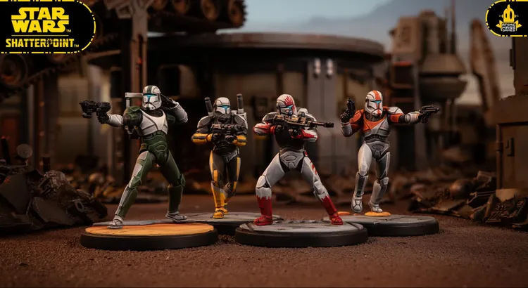 A trio of detailed miniature figures from the Delta Squad, featuring Clone Commandos Boss, Fixer, and Scorch, stands on circular bases. Each figure is uniquely painted, showcasing their distinct armor designs: Boss in gray with red accents, Fixer in gray with blue details, and Scorch in gray with orange highlights. The background depicts a desolate, industrial landscape, enhancing the battle-ready theme of the scene.